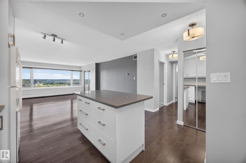 White kitchen featuring quartz counters, hardwood flooring, electric stove, microwave hood fan, space for a dishwasher, and refrigerator. - #803 10011 123 St Nw, Edmonton, AB 