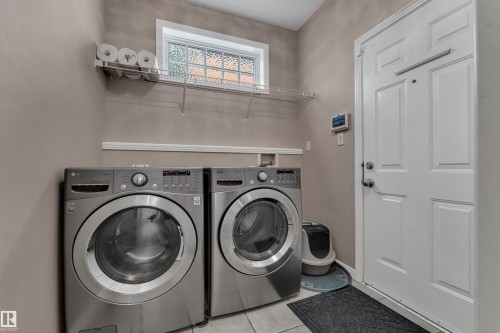Laundry area with a built-in wire shelf, a glass block window, and a paneled door - 1226 Mcallister Way Sw, Edmonton, AB 