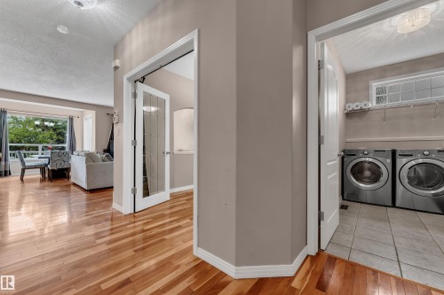 Hardwood flooring, laundry area with tiled flooring, large bay window, and a glass-paneled interior door - 1226 Mcallister Way Sw, Edmonton, AB 