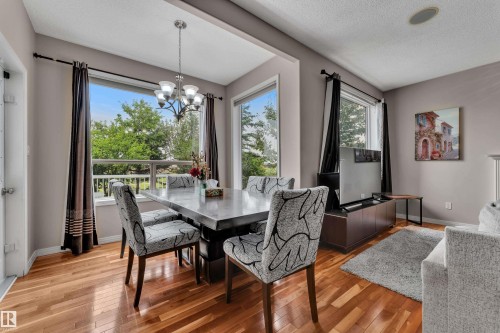Hardwood flooring, large windows, recessed ceiling light, ceiling-mounted speaker, and a modern light fixture - 1226 Mcallister Way Sw, Edmonton, AB 