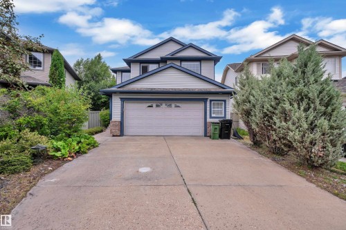 Multi-story residence featuring light-colored siding with dark trim, a two-car garage, and a concrete driveway - 1226 Mcallister Way Sw, Edmonton, AB 