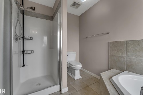 Enclosed shower with a handheld showerhead, ceramic tile flooring, and a built-in tub with tile surround - 1226 Mcallister Way Sw, Edmonton, AB 