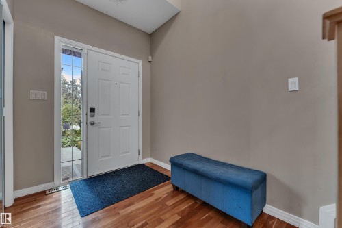 Wood-finish flooring, white paneled door with glass sidelight, vaulted ceiling, and light-toned walls - 1226 Mcallister Way Sw, Edmonton, AB 