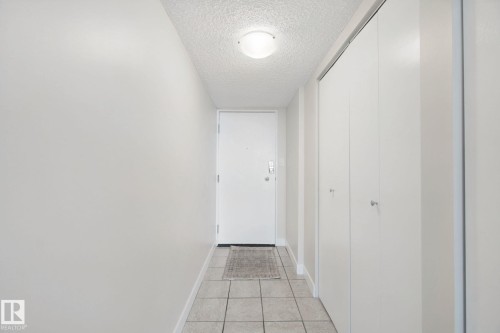 Entryway featuring light-toned tile flooring, flush-mount ceiling lighting, and multiple bi-fold closet doors - #104 8745 165 St Nw, Edmonton, AB 