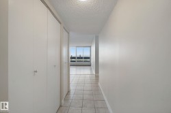 Hallway with light-toned tile flooring, white walls, and built-in closet doors - 