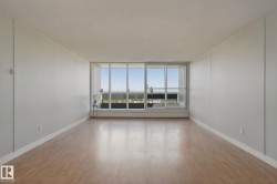 Expansive room featuring wood-finish flooring, white baseboards, and a large window with a distant landscape - 