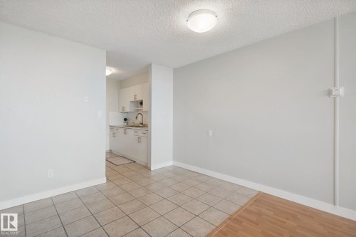 Two-tone flooring with tile and wood-finish sections, white painted walls, and a flush-mount ceiling light - #104 8745 165 St Nw, Edmonton, AB 