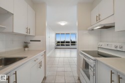 Kitchen featuring white cabinetry with gold-tone hardware, white tiled backsplash, and light-toned countertops - 