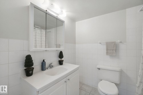 White tile-surround bath with a built-in vanity, medicine cabinet, and overhead light fixture - #104 8745 165 St Nw, Edmonton, AB 