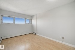 Light wood-finish flooring, multiple windows, baseboard heating, and light-toned wall finishes - 