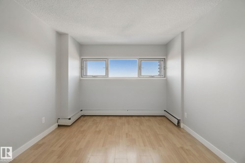 Light wood-finish flooring, white walls, and a multi-pane window - #104 8745 165 St Nw, Edmonton, AB 