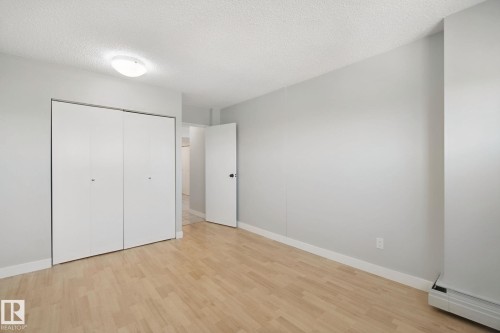 Wood-finish flooring with white baseboards, light gray wall paint, and a textured ceiling - #104 8745 165 St Nw, Edmonton, AB 