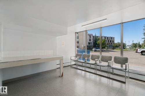 Expansive windows providing abundant natural light, a long built-in counter with a tiled backsplash, and recessed overhead lighting - #104 8745 165 St Nw, Edmonton, AB 