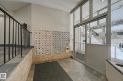 Slate tile flooring, glass and aluminum entry doors, full wall of individual mailboxes, and wrought iron railing - 