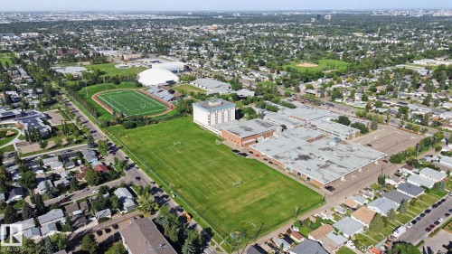 Aerial perspective of a developed urban area featuring residential properties, expansive green spaces, and community amenities - #104 8745 165 St Nw, Edmonton, AB 