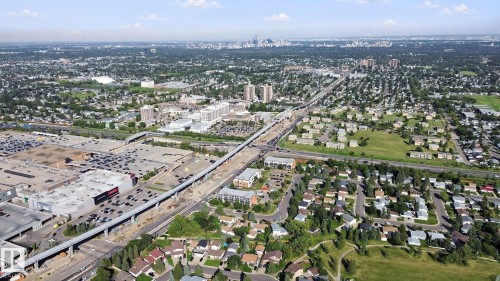 Expansive aerial perspective showcasing a residential neighborhood, commercial developments, and an elevated transit line - #104 8745 165 St Nw, Edmonton, AB 