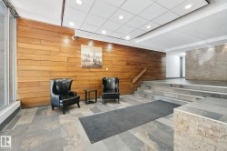 Wood-paneled wall, recessed ceiling lighting, stone tile flooring, multi-level stone steps, and a stone-clad half-wall - 