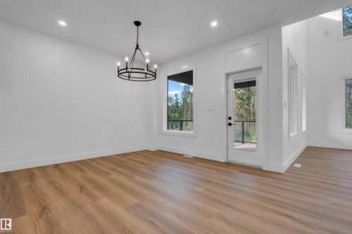 Spacious interior with wood-finish flooring, recessed lighting, and a contemporary black chandelier - 57 Meadowgrove Lane, Spruce Grove, AB - Indoor Photo Showing Other Room