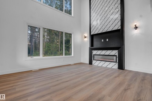 Two-story architectural feature wall with an electric fireplace, flanked by sconce lighting - 57 Meadowgrove Lane, Spruce Grove, AB - Indoor Photo Showing Other Room With Fireplace