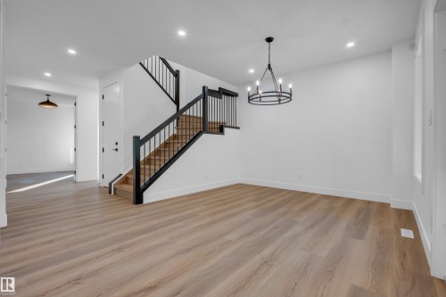 Open concept interior featuring light wood-finish flooring, a contemporary black metal chandelier, and recessed lighting - 57 Meadowgrove Lane, Spruce Grove, AB - Indoor Photo Showing Other Room