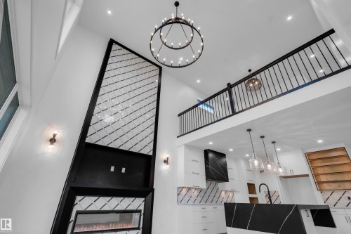 Soaring ceilings frame an open-concept living area with a contemporary fireplace featuring an integrated firebox - 57 Meadowgrove Lane, Spruce Grove, AB - Indoor Photo Showing Other Room