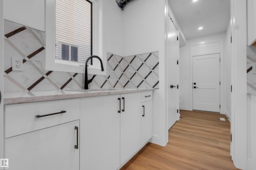 Utility area featuring white cabinetry with matte black hardware, a light-colored countertop, and a black gooseneck faucet - 57 Meadowgrove Lane, Spruce Grove, AB - Indoor Photo Showing Other Room