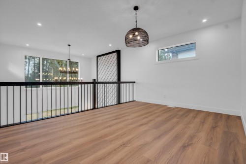 Spacious upper-level landing featuring wood-finish flooring, a contemporary black metal balustrade, and a decorative screen element - 57 Meadowgrove Lane, Spruce Grove, AB - Indoor Photo Showing Other Room