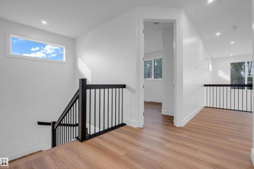Upper-level landing featuring wood-finish flooring, a contemporary black metal railing, white walls, recessed lighting, and ample natural light from multiple windows - 57 Meadowgrove Lane, Spruce Grove, AB - Indoor Photo Showing Other Room