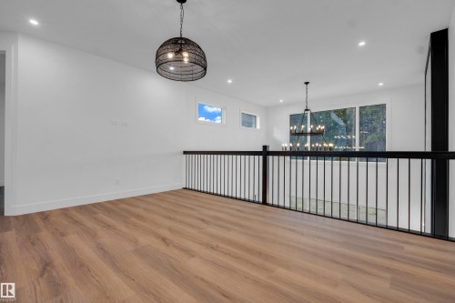 Open concept loft area featuring wood-finish flooring, a modern black metal railing, and recessed ceiling lighting - 57 Meadowgrove Lane, Spruce Grove, AB - Indoor Photo Showing Other Room