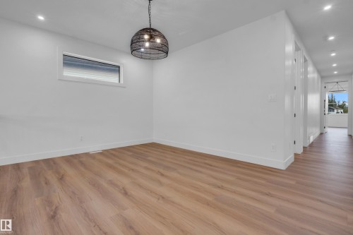 Spacious room featuring wood-finish flooring, a contemporary black metal pendant light fixture, and recessed lighting - 57 Meadowgrove Lane, Spruce Grove, AB - Indoor Photo Showing Other Room