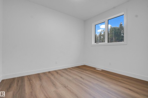 Bright interior space featuring a window with white trim, wood-finish flooring, white baseboards, and white painted walls - 57 Meadowgrove Lane, Spruce Grove, AB - Indoor Photo Showing Other Room