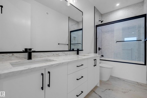 Dual vanity with white cabinetry, matte black hardware, and stone countertops - 57 Meadowgrove Lane, Spruce Grove, AB - Indoor Photo Showing Bathroom