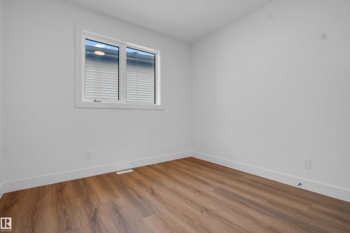 Bright room featuring wood-finish flooring, white walls, and a large window with white blinds - 57 Meadowgrove Lane, Spruce Grove, AB - Indoor Photo Showing Other Room
