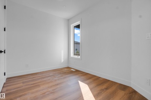 Room with warm wood-finish flooring and white baseboards - 57 Meadowgrove Lane, Spruce Grove, AB - Indoor Photo Showing Other Room