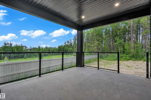 Covered outdoor patio featuring a concrete surface, glass panel railing with black metal posts, and recessed ceiling lighting - 57 Meadowgrove Lane, Spruce Grove, AB - Outdoor With Deck Patio Veranda With Exterior