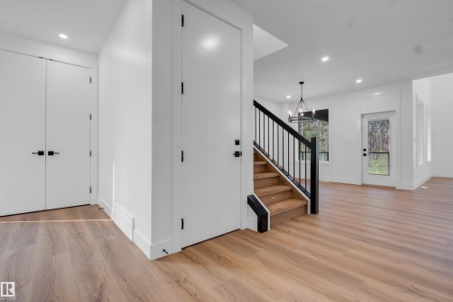 Foyer featuring wood-finish flooring, a contemporary staircase with black railings, recessed lighting, and a modern chandelier - 57 Meadowgrove Lane, Spruce Grove, AB - Indoor Photo Showing Other Room