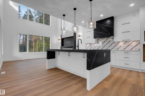 Modern kitchen island with a waterfall countertop, featuring a matte black faucet and pendant lighting - 57 Meadowgrove Lane, Spruce Grove, AB - Indoor Photo Showing Kitchen With Upgraded Kitchen