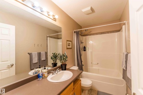 Bathroom featuring a single vanity with an integrated sink, a built-in shower/tub combination, and a full-width mirror - 5092 Thibault Way Nw, Edmonton, AB 