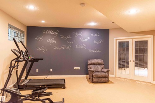 Recessed lighting illuminates a spacious room featuring a painted accent wall and light-colored carpeting - 5092 Thibault Way Nw, Edmonton, AB 