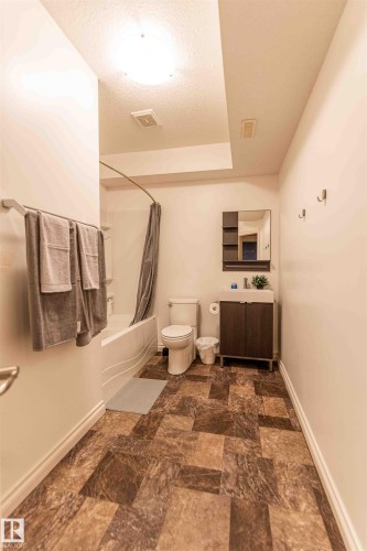 Bathroom featuring a bathtub with shower, toilet, and a vanity with a rectangular sink - 5092 Thibault Way Nw, Edmonton, AB 