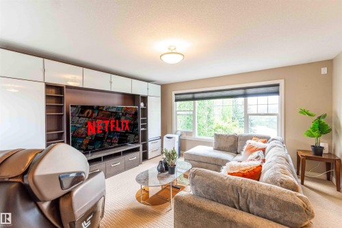 Built-in media center with integrated shelving and white cabinetry, large windows with roller shades, and neutral wall tones - 5092 Thibault Way Nw, Edmonton, AB 