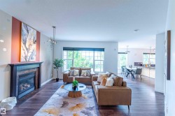 Open concept living space featuring wood-finish flooring, a built-in fireplace with a stone surround, and multiple windows - 