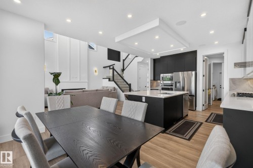 Open-concept living area featuring wood-finish flooring, recessed lighting, and a contemporary kitchen with a large island - 16304 19 Avenue Sw, Edmonton, AB 
