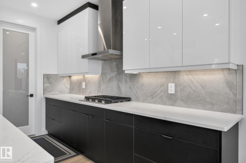 Modern kitchen featuring white upper cabinetry and black lower cabinetry with integrated hardware - 16304 19 Avenue Sw, Edmonton, AB 