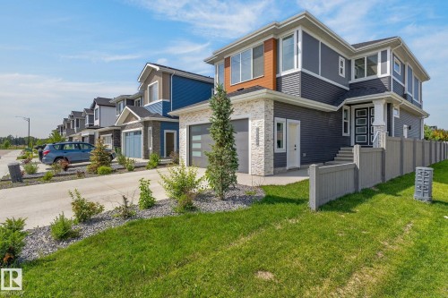 Contemporary architectural design featuring dark gray siding, light stone accents, and a distinctive wood-look panel - 16304 19 Avenue Sw, Edmonton, AB 