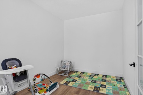 Room featuring wood-finish flooring, white baseboards, and a white wall finish - 16304 19 Avenue Sw, Edmonton, AB 