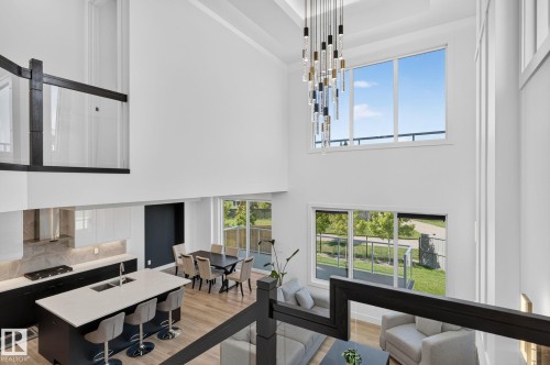Two-story living area with high ceilings, contemporary chandelier, and expansive windows - 16304 19 Avenue Sw, Edmonton, AB 