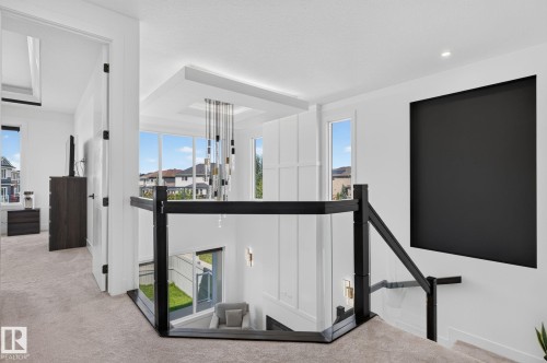 Modern interior landing featuring a black metal and glass railing, recessed lighting, and a contemporary chandelier - 16304 19 Avenue Sw, Edmonton, AB 