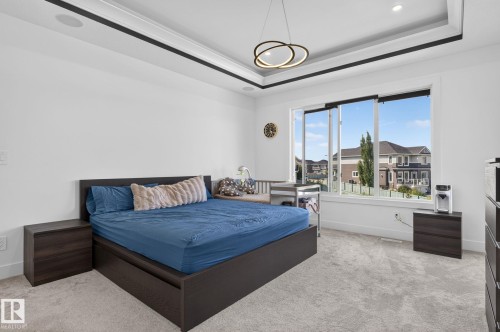 Recessed ceiling with contrasting trim, contemporary ceiling light fixture, expansive window, light-colored carpeting, and white painted walls - 16304 19 Avenue Sw, Edmonton, AB 