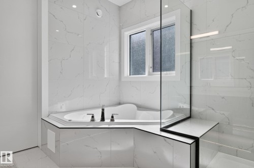 Bathroom featuring a corner soaking tub, white marble-look wall and floor tiling, frosted window, and a clear glass shower enclosure - 16304 19 Avenue Sw, Edmonton, AB 